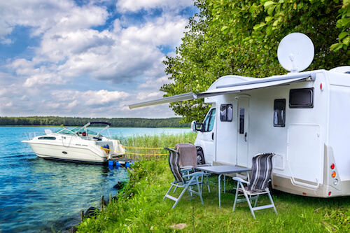 A white trailer parked next to the water.